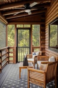 a porch of a log cabin with chairs and a ceiling fan at Riverside Rose Cabin: Luxe*LogCabin*MtnView*Sleeps12*Secluded*Shenandoah in Rileyville