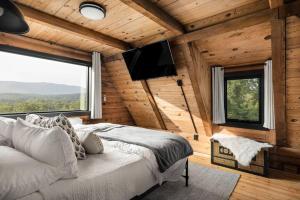 a bedroom with a bed and a flat screen tv at Riverside Rose Cabin: Luxe*LogCabin*MtnView*Sleeps12*Secluded*Shenandoah in Rileyville