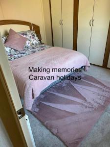 a bedroom with a bed with a pink blanket at Making Memories Holiday Caravan in Skegness