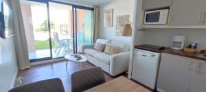 cocina y sala de estar con sofá y microondas en Chez Adriana Appartement Cosy avec Jardin, proche plage en Grimaud