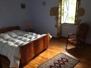 ein Schlafzimmer mit einem Bett, einem Stuhl und einem Fenster in der Unterkunft Ferme typique de Gascogne 