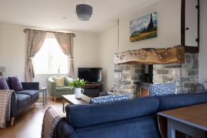 a living room with blue couches and a stone fireplace at Family Country Cottage with Stunning Mountain Views in Myddfai