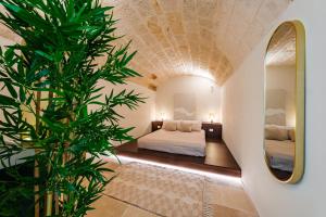 a bedroom with a bed and a large plant at HelloAPULIA Charming Palazzo Clemente - self-catering suites with aircondition in Monopoli