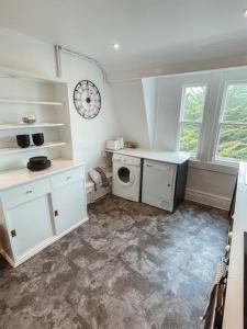 a kitchen with white cabinets and a washing machine at The Great Pulteney Penthouse, Bath City Centre in Bath