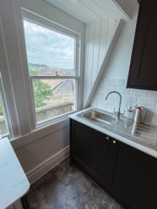 a kitchen with a sink and a window at The Great Pulteney Penthouse, Bath City Centre in Bath