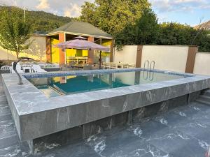a swimming pool with a table and an umbrella at Xanagah Villa in İsmayıllı