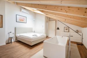 a white bedroom with a bed and a bath tub at Casa Al Sole in Tenno