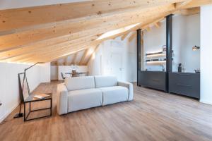 a living room with a white couch and wooden ceilings at Casa Al Sole in Tenno