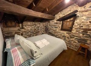 1 dormitorio con 1 cama en una pared de piedra en Las Casitas de Requeixo, en Requeixo