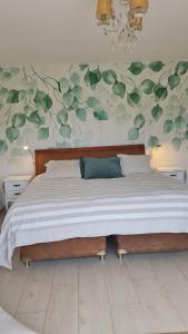 1 dormitorio con 1 cama grande con hojas verdes en la pared en Ventarrón Pueblomio Manantiales, en Manantiales