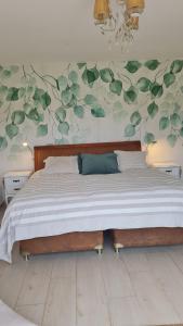 a bedroom with a large bed with green leaves on the wall at Ventarrón Pueblomio Manantiales in Manantiales