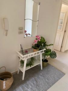 una consola blanca con plantas y un espejo en Modern chic haven, en Amán