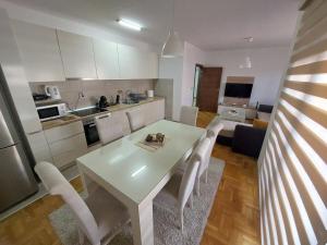 Apartment Gelić Family في كومانوفو: مطبخ وغرفة طعام مع طاولة وكراسي بيضاء