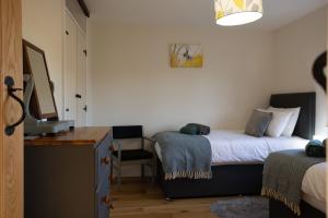 a bedroom with two beds and a desk and a television at Brecon Beacons Cottage with Stunning Country Views in Myddfai