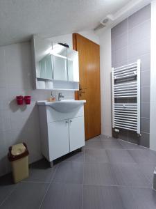 a bathroom with a white sink and a wooden door at Guesthouse Nikolina in Korenica