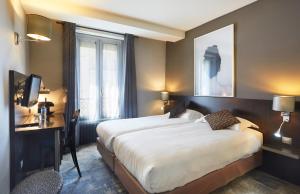 a hotel room with two beds and a desk at Logis h&ocirc;tel Jardin de Villiers in Paris