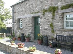 ein Steingebäude mit einer grünen Tür und einer Bank in der Unterkunft Alltybrain Farm Cottages and Farmhouse B&B in Brecon