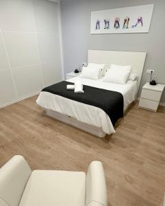 ein weißes Schlafzimmer mit einem Bett und einer Couch in der Unterkunft APARTAMENTOS FREIXO-Rias Baixas in Cangas