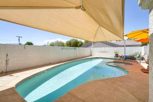 uma piscina com um guarda-sol, uma mesa e cadeiras em Sunny Las Vegas Studio with Shared Pool and Backyard! em Las Vegas