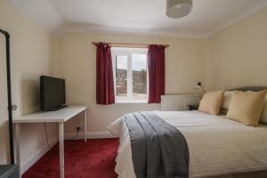 Un dormitorio con una cama y un televisor y una ventana. en Fawley, en Lyme Regis