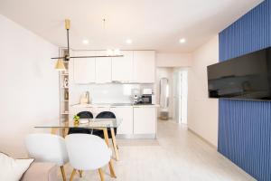 a kitchen with white cabinets and a table and chairs at Palangre Luxury Apartment in Torrevieja