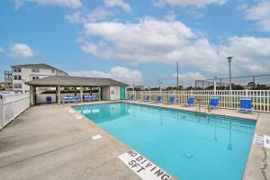 a swimming pool with blue chairs and a building at Ocean Front Emerald Isle Vacation Rental Property in Emerald Isle