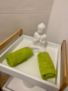 a figurine of a buddha and two green towels at Ferien-Wohnung für 1-4 Pers in Seenähe in Timelkam