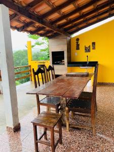 een houten tafel en stoelen in een kamer met een gele muur bij Casa de Temporada em Capitólio - Ternure in Capitólio