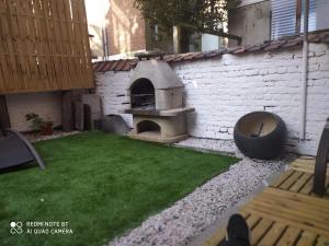 einen Pizzaofen im Freien im Hinterhof mit Rasen in der Unterkunft Appartement Magnifique dans un beau cadre in Brüssel