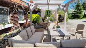 patio z białą pergolą, stołem i krzesłami w obiekcie Folwark Leszczynówka w Srebrnej Górze