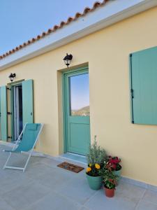 une maison avec une porte verte et une chaise sur une terrasse dans l'établissement Phileo Villas, à Platithriás