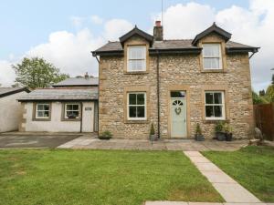 a stone house with a lawn in front of it at Netherbeck Cottage in Carnforth