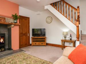 a living room with a tv and a fireplace at Netherbeck Cottage in Carnforth