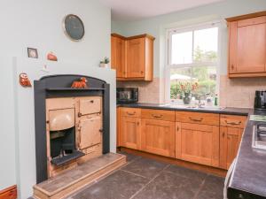 a kitchen with a fireplace in the middle of it at Netherbeck Cottage in Carnforth