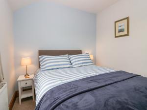 a bedroom with a bed with a blue and white blanket at Netherbeck Cottage in Carnforth