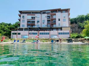 a building on the beach with people in the water at Sunrise Beach - Lake View Deluxe Apartment in Peštani