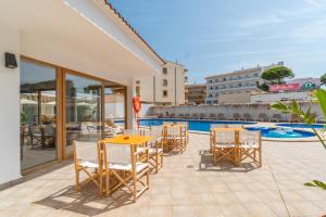 a patio with a table and chairs next to a swimming pool at Hostal Alcina in Cala Ratjada