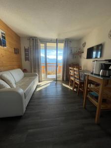 a living room with a couch and a table and a kitchen at Charmant Studio 4P Alpe d'huez in LʼHuez