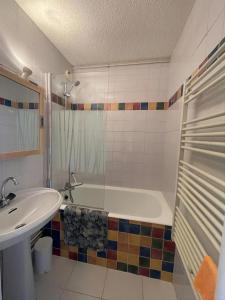 a bathroom with a bath tub and a sink at Charmant Studio 4P Alpe d'huez in LʼHuez