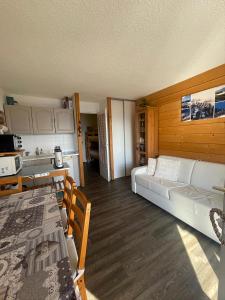 a living room with a white couch and a kitchen at Charmant Studio 4P Alpe d'huez in LʼHuez