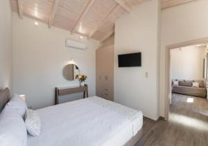 a white bedroom with a bed and a television at Nikolaos Apartment 2 in Nydri