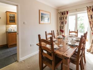 a dining room with a wooden table and chairs at 24 Dolithel in Tywyn