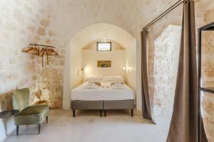 a bedroom with a bed and a chair in a room at Trulli Meridiem con Piscina in Ostuni