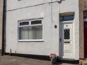 a white house with a door and a flower pot at Field View in Saltburn-by-the-Sea