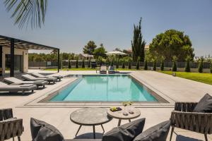 a swimming pool with chairs and a table and a patio at AL MARE VILLAS in Lixouri