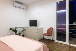 Schlafzimmer mit einem Bett, einem TV und einem Stuhl in der Unterkunft Rosina Apartment surfing bed&vacation in Terrasini