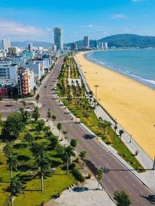 a beach with palm trees and a road next to the ocean at VIVUVIVU77 in Quy Nhon