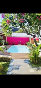 a swimming pool in a yard with a pink wall at Villa with pool close to the sea in Saint-Gilles les Bains