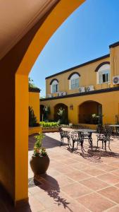 un patio con bancos y una mesa en un edificio en Hotel San Carlos en San Antonio de Areco