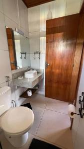 a bathroom with a toilet and a sink and a wooden door at Pedacinho de Chão Chalés in Visconde De Maua